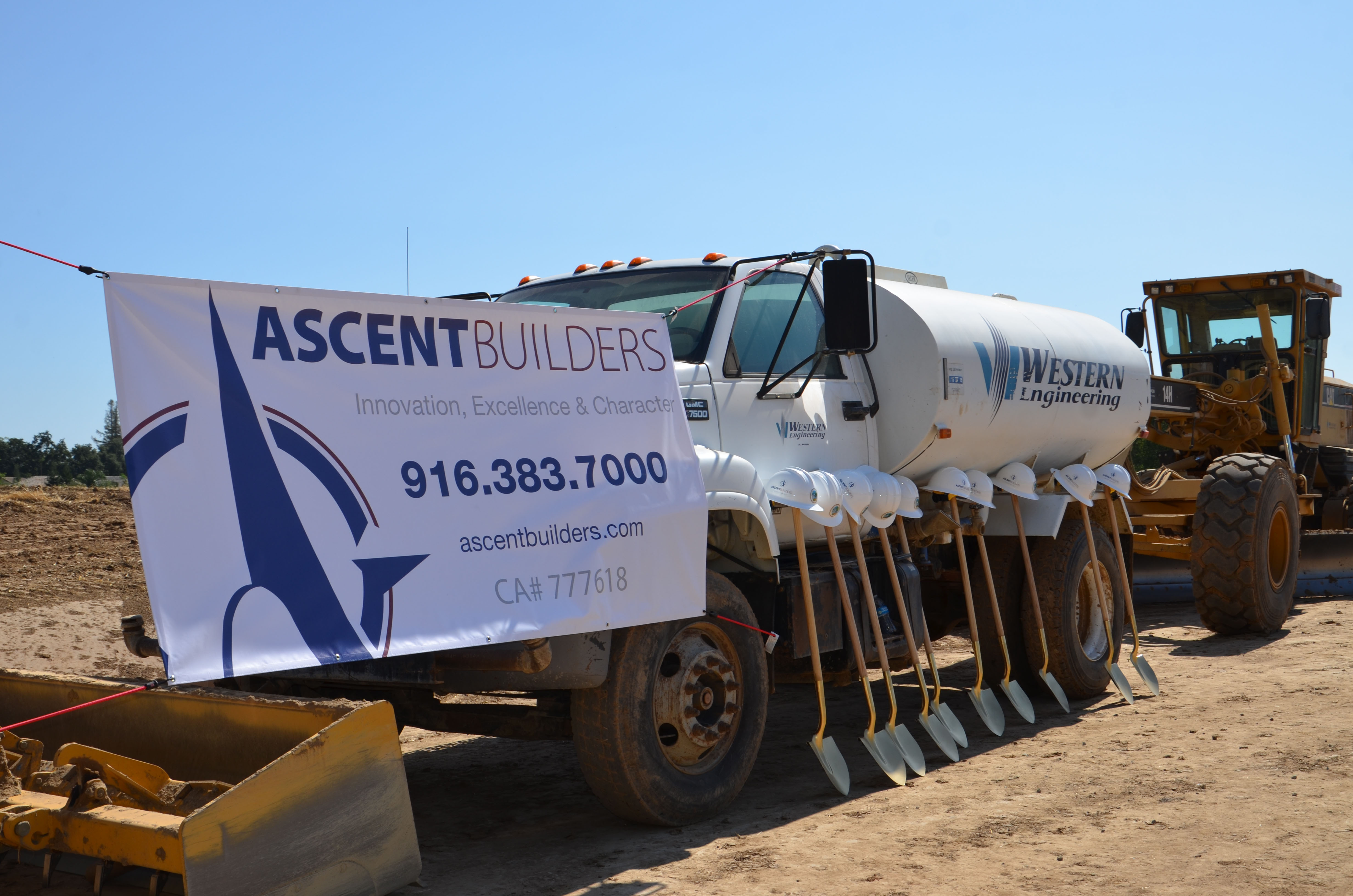 The groundbreaking shovels and hardhats lined up in front of Ascent Builders trucks